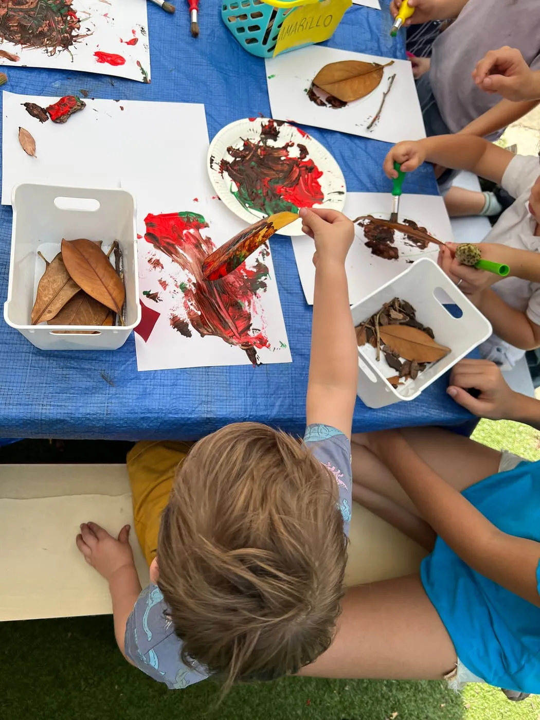 Children painting with leaves at a craft table